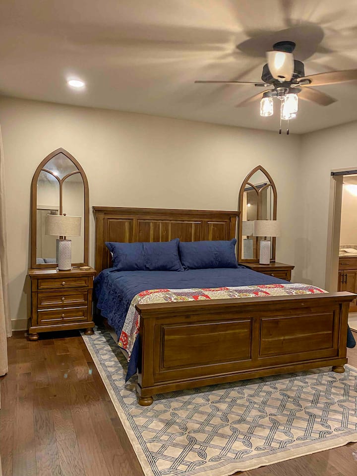 Primary bedroom on first floor with king bed, water views, walk in closet, luggage rack, dresser, iron, ironing board, broom, dustpan, private primary bath with large walk in shower and double vanity. 