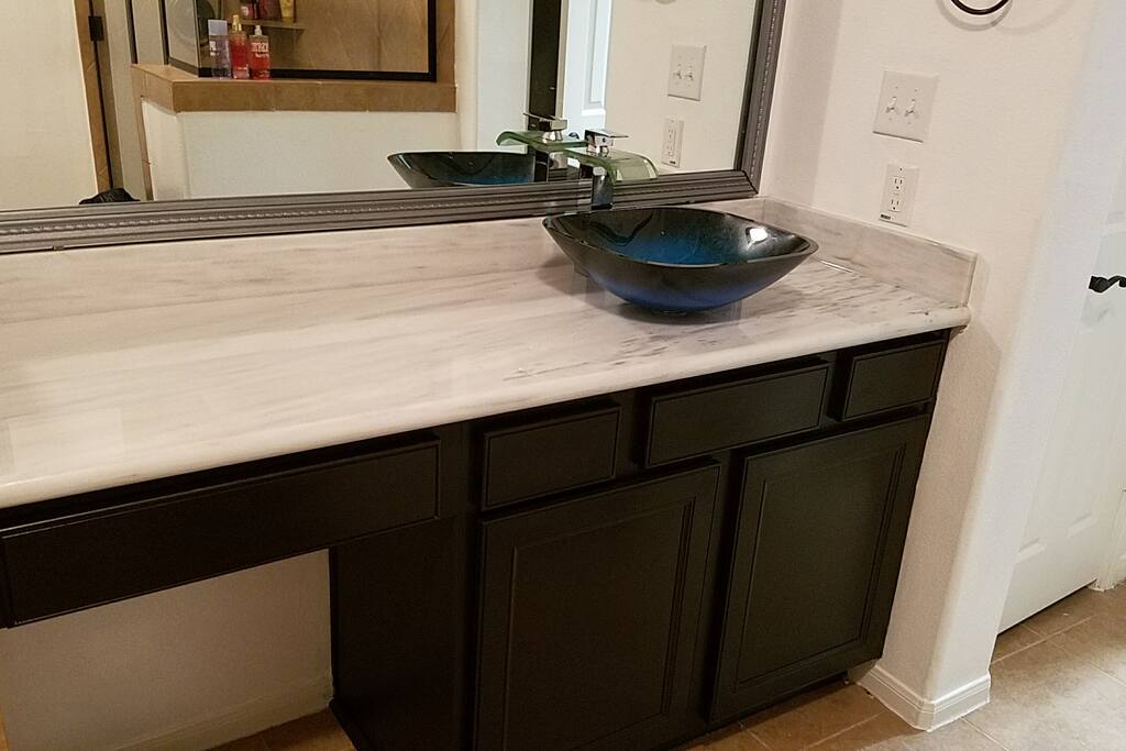 Luxurious and contemporary master bathroom with Carerra granite and glass vessel sinks with waterfall faucets.