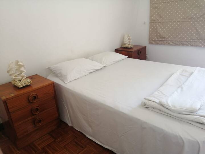 Main bedroom with queen bed, mosquito net over the bed and AC unit. Has a balcony that has a partial sea view.