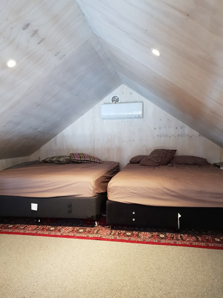 Dormitorio loft con dos camas tamaño matrimonial.