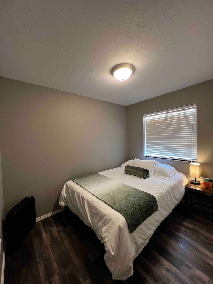 ห้องนอนแรกพร้อมเตียงควีนไซส์เมมโมรี่โฟมตู้เสื้อผ้าขนาดใหญ่และโคมไฟข้างเตียงที่ชาร์จไฟได้