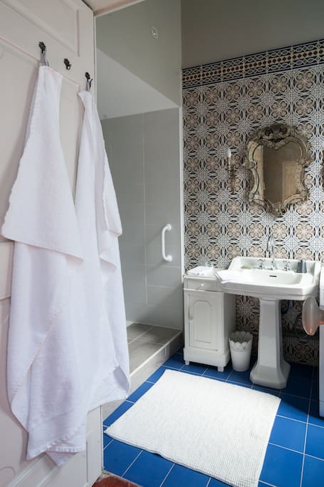 Charming bathroom with cheery azure floor tiles, Venetian mirror, and pedestal sink in a luxurious French apartment with classic French decor. #bathroomdecor #French #bathroomdesign