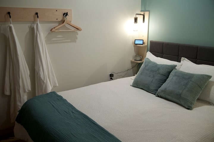 Queen bed area with bath robes, charging stations