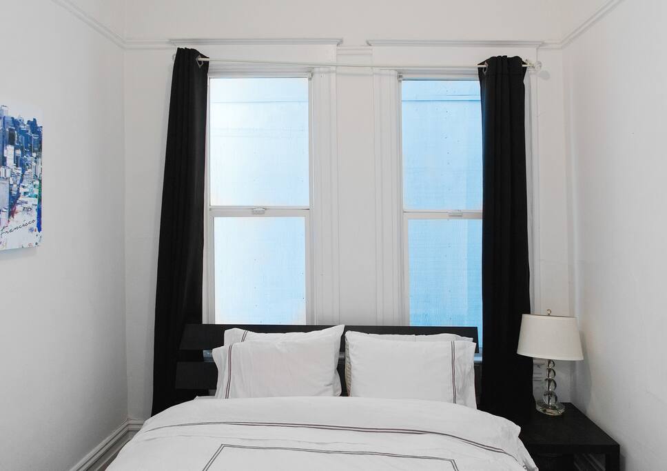 Queen sized bed with four pillows and luxury sheets.
