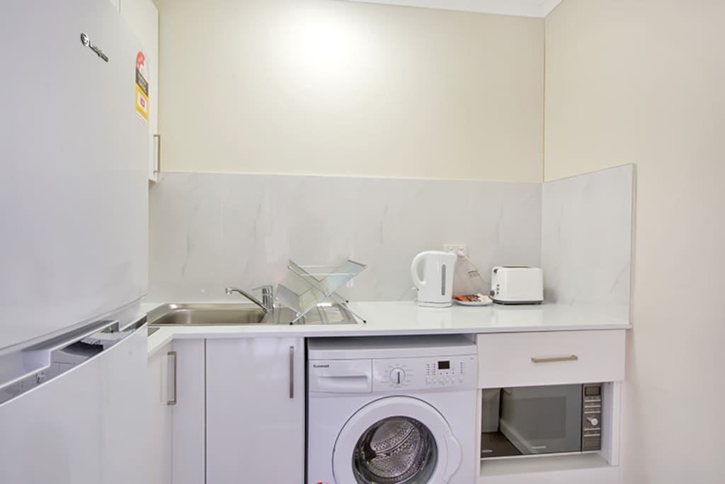 Modern kitchen with full-sized fridge/freezer and washing machine.