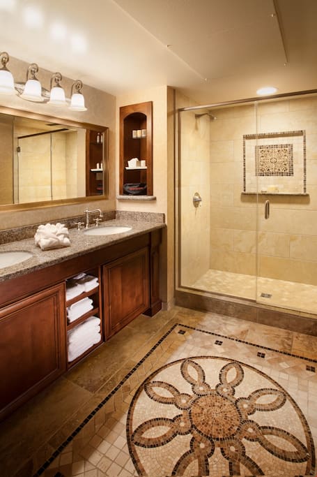 The spacious natural stone bathroom features a glass-enclosed shower and comes fully-equipped with plush bathrobes and Fresh brand amenities