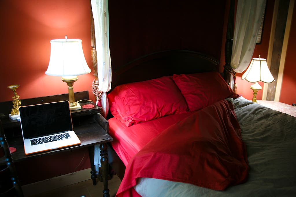 plush, comfy bedding and a great, 4 poster, queen canopy bed. a work table/desk in the room.