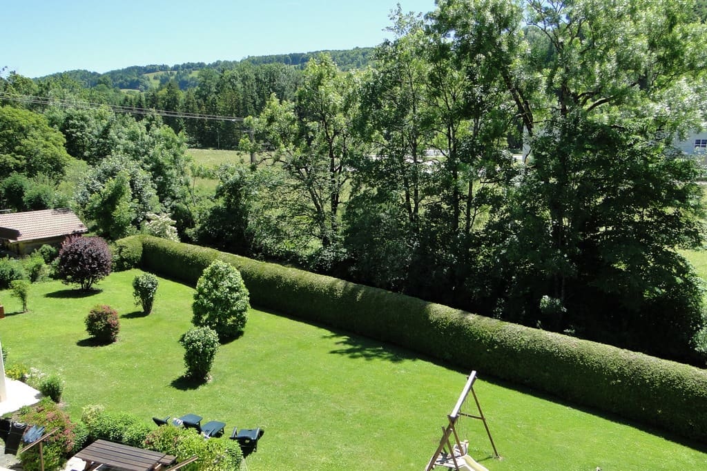Vue dégagée sur le jardin arboré et la montagne