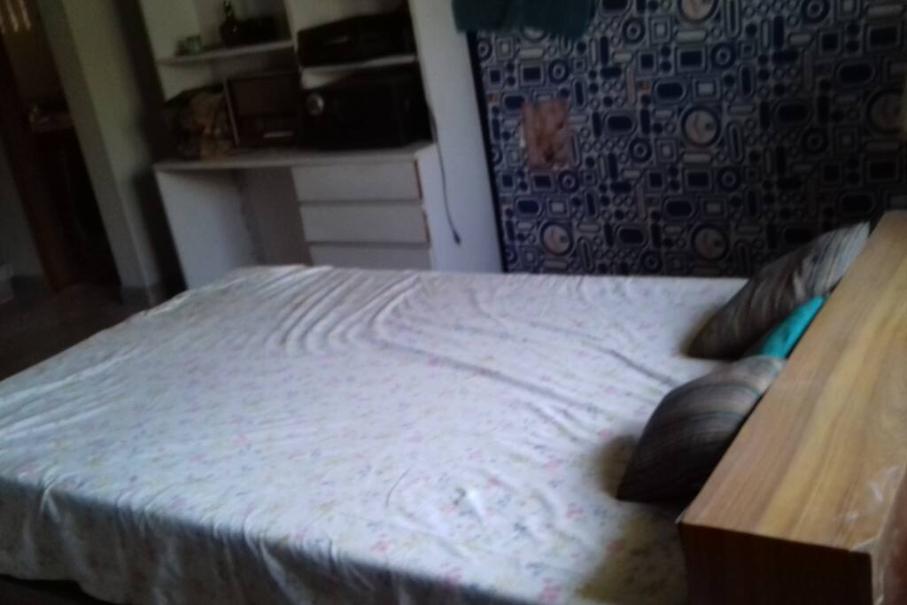 The bed and bookshelf/tapestry in the background.