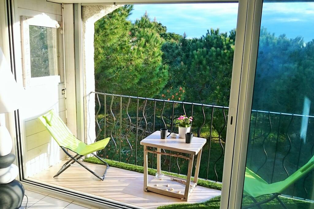 La loggia, sa table basse, ses fauteuils de jardin et sa vue sur la pinède verdoyante et sans vis-à-vis
