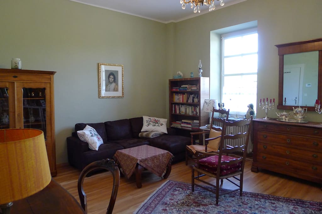 Großzügiges Wohnzimmer mit Sofa, Arbeitsplatz, TV und einem Einzelbett (Foto folgt)