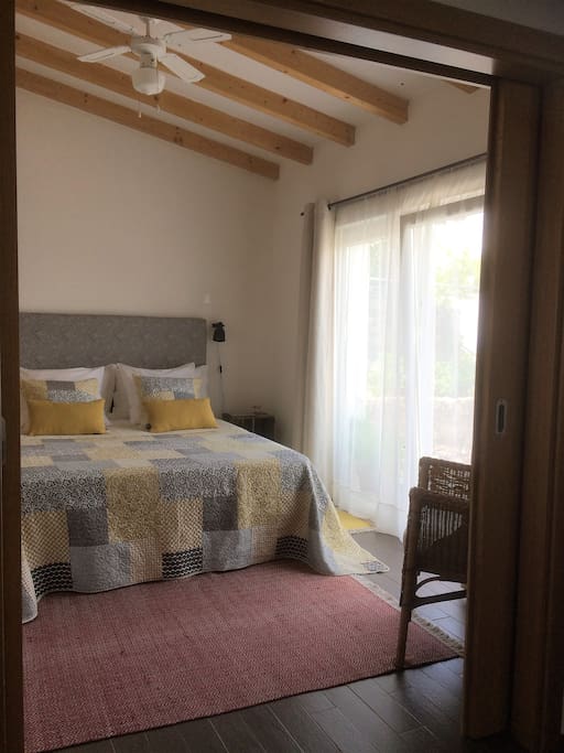 Bright and airy bedroom with air-conditioning and ceiling fan.