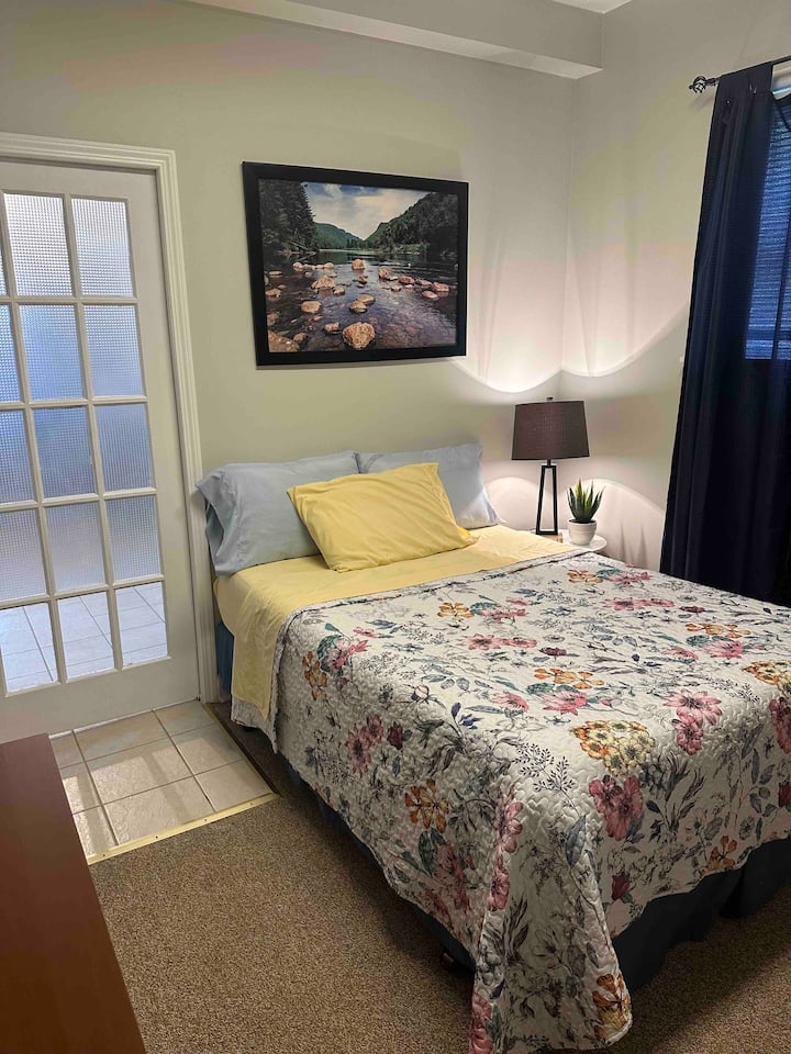 Hay una puerta de bolsillo que separa el dormitorio del área de la cocina/sala de estar.

Cama doble con sábanas suaves y acogedora ropa de cama, mesa auxiliar y lámpara.