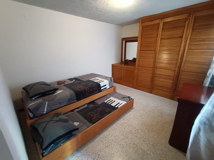 غرفة نوم صغيرة 2 مع سريرين مفردين وخزانة.