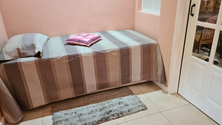Dormitorio 2 con cama individual, ventilador de techo, TV inteligente y estante para ropa.