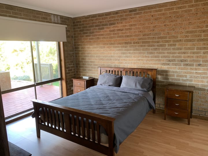 Dormitorio grande en la planta baja con traje de dormitorio tamaño queen de madera maciza, chico alto con vistas al jardín trasero.