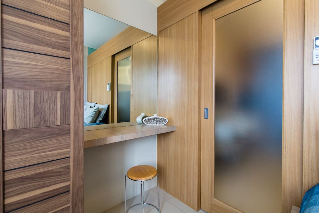 Large mirror and a dresser next to closet that doubles as a work/laptop desk
