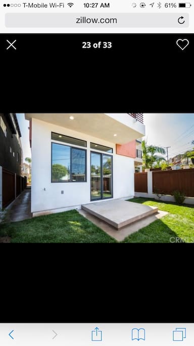 Backyard features BBQ and patio chairs.