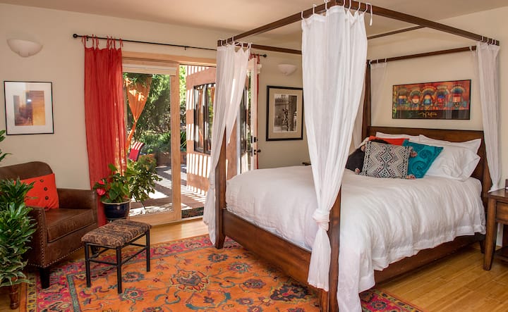 Chumba kikuu cha kulala cha kimapenzi chenye milango miwili ya Kifaransa iliyofunguliwa kwenye baraza ya kujitegemea.