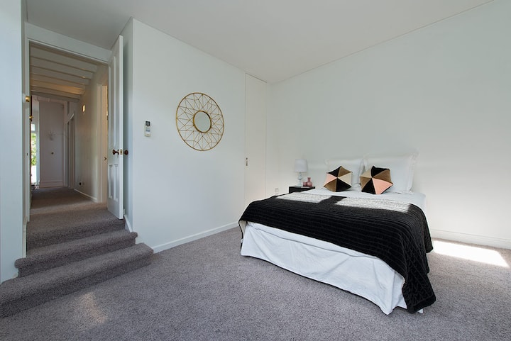 ห้องนอนใหญ่พร้อมเตียงคิงไซส์และผ้าปูที่นอนหรูหราตู้เสื้อผ้าขนาดใหญ่สองตู้และโต๊ะทำงานเปิดไปยังสวนหลังบ้านที่มีทางเข้าแยกต่างหากหากต้องการ 