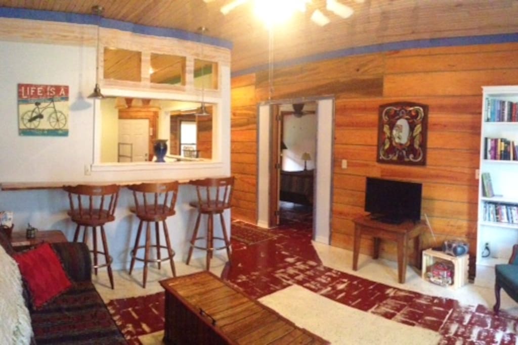 Nice open-flow space with rough sawn lumber walls, pine-top bar, reading corner, and sofa sleeper.