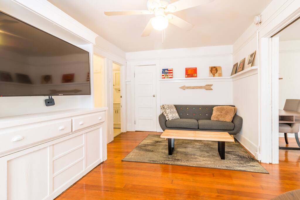 The living area is highlighted by gorgeous wood floors, lots of light, a cozy sofa and large flat screen TV with Apple TV
