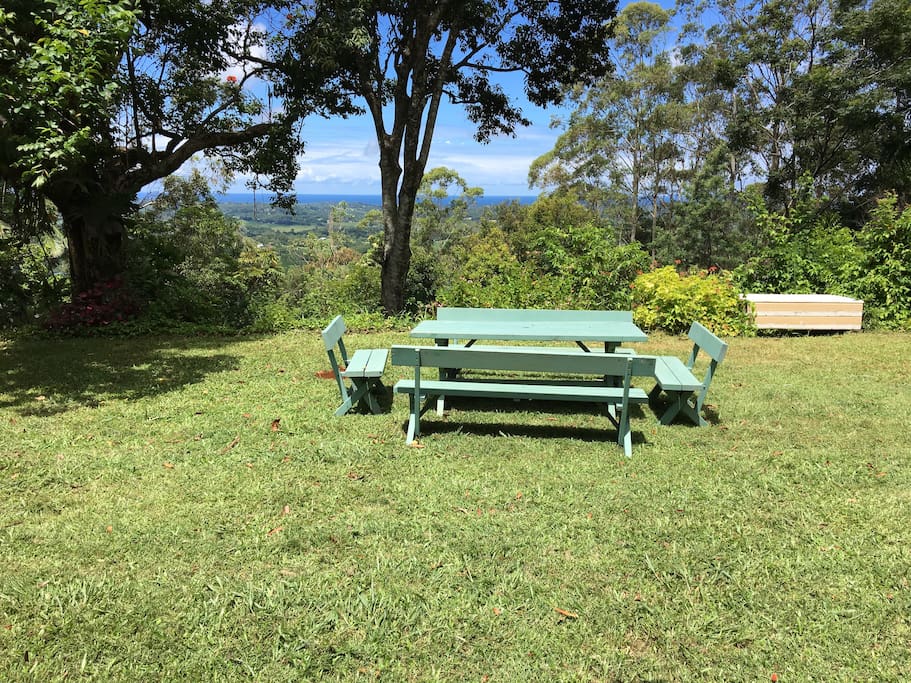 Expansive garden with ocean views for dining, playing, lying on a rug under a tree.