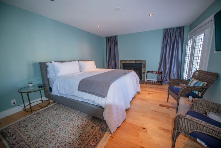 Главна спална соба со камин на дрва. Француските врати се отвораат кон балконот на горниот кат. 