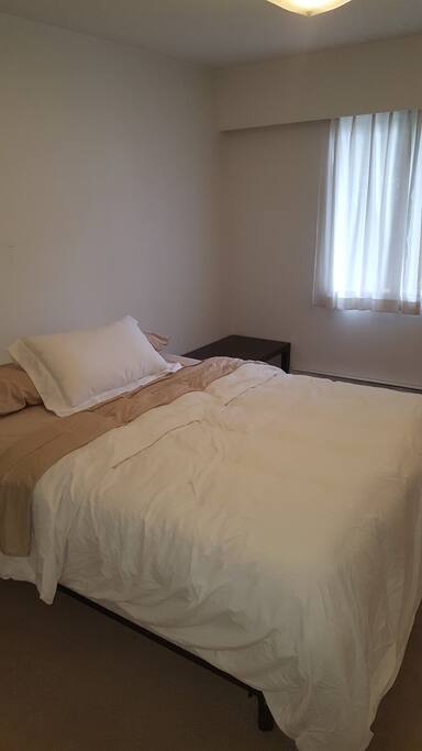 Queen size bed with night stand and luggage table. Closet with hangers.