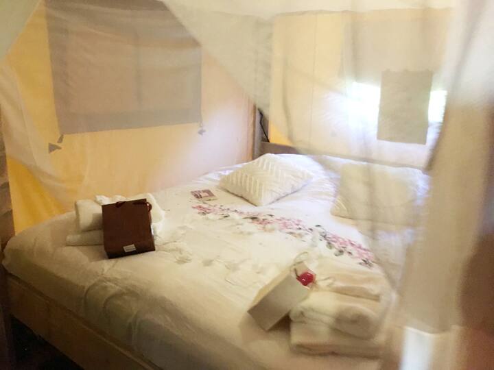 Un grand lit king size dans une tente Glamp