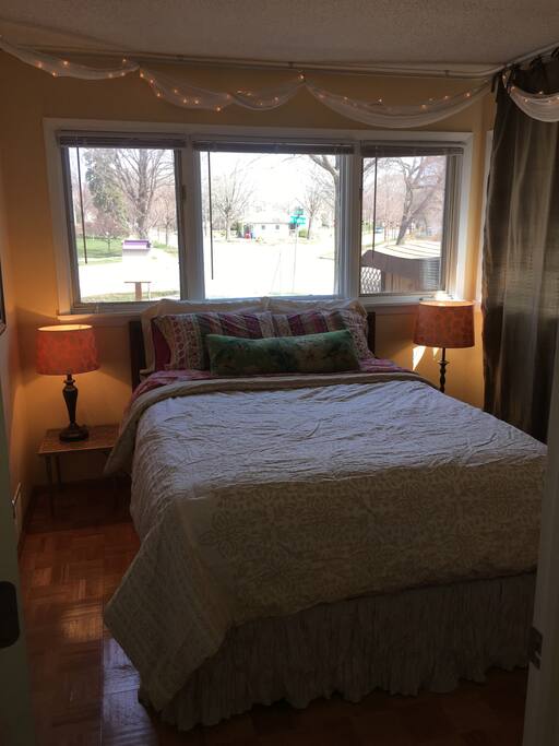 Queen bed with hypoallergenic pillow top cushion, ambient lighting, blackout curtain panel, and minibinds above bed.