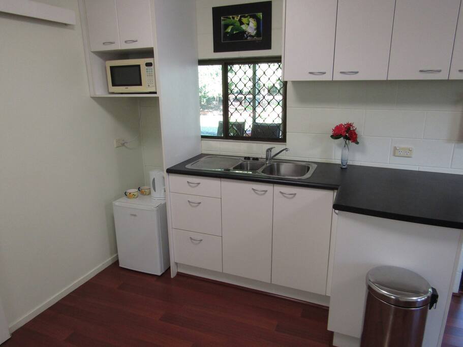 Kitchen with sink, fridge (bar), microwave, cutlery, crockery, kettle, toaster, sandwich toaster.