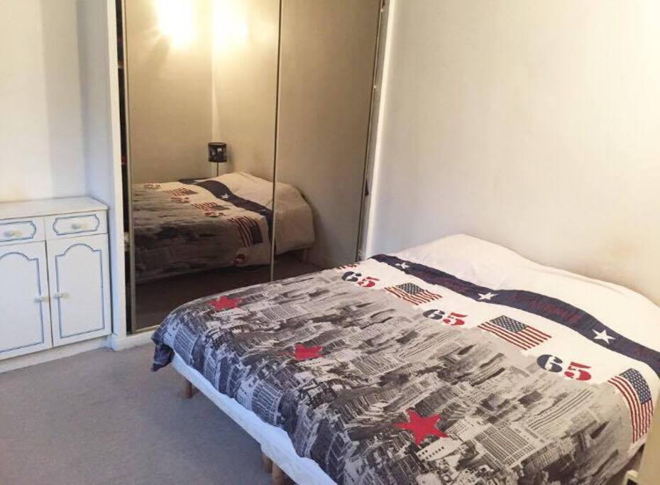 une grande chambre avec lit double, un grand placard et une table à repasser