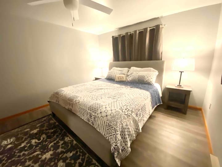 Chumba cha kulala cha ghorofa kuu chenye kitanda aina ya king na mapazia ya kuzuia mwanga. Kidhibiti cha joto cha umeme ndani ya chumba; hakuna AC lakini feni ya dari imejumuishwa.