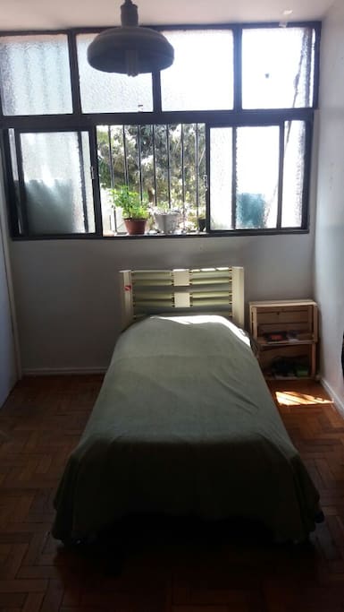 Quarto simples, iluminado, banheiro exclusivo.