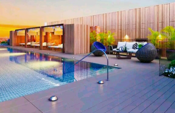An elegant outdoor pool area is showcased, featuring a serene swimming pool reflecting the sunset. Comfortable lounge chairs and stylish seating can be seen along the pool's edge, complemented by tropical plants that enhance the relaxing atmosphere.