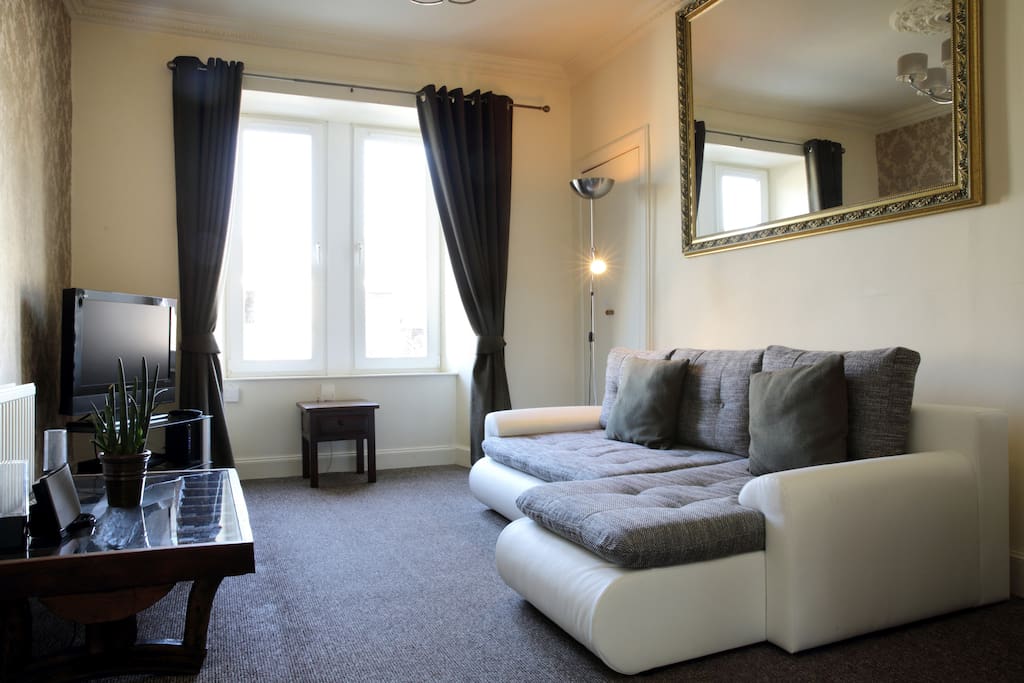 Bright and cozy living room with large corner leather sofa bed.