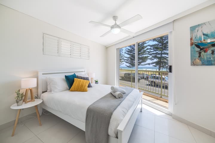 A stylish & bright master bedroom enjoys sea views and includes a queen-size bed and built-in wardrobe