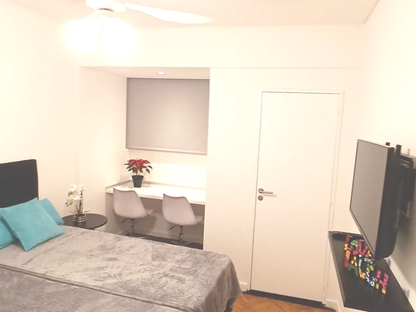 Vista de tv smart y ventilador en formato con 2 camas individuales en dormitorio en suite