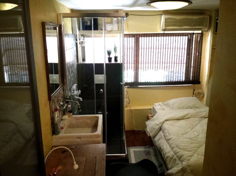 View of OneStep Suite, with the comfortable bed, the huge window with the lovely view in our safe & calm neighborhood, the kitchen and the shower with the toilet!
