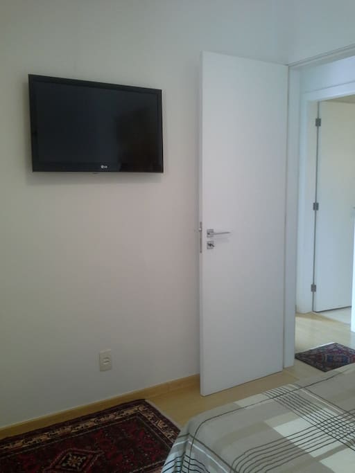 Quarto individual com cama de casal e tv.
