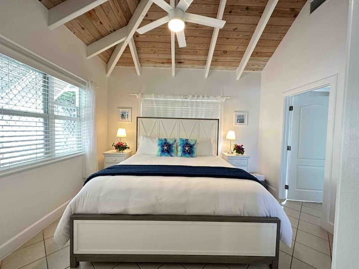 Chumba bora cha kulala chenye dari nzuri za mbao za caribbean. Pumzika katika kitanda hiki cha kifahari chenye godoro la starehe zaidi na umeamka jua likichomoza dirishani. Mlango ulio upande wa kulia ni bafu lako la kujitegemea.