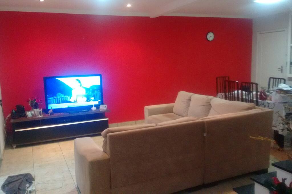 Sala ampla com sofá em L, TV 49, rebaixamento de geso.