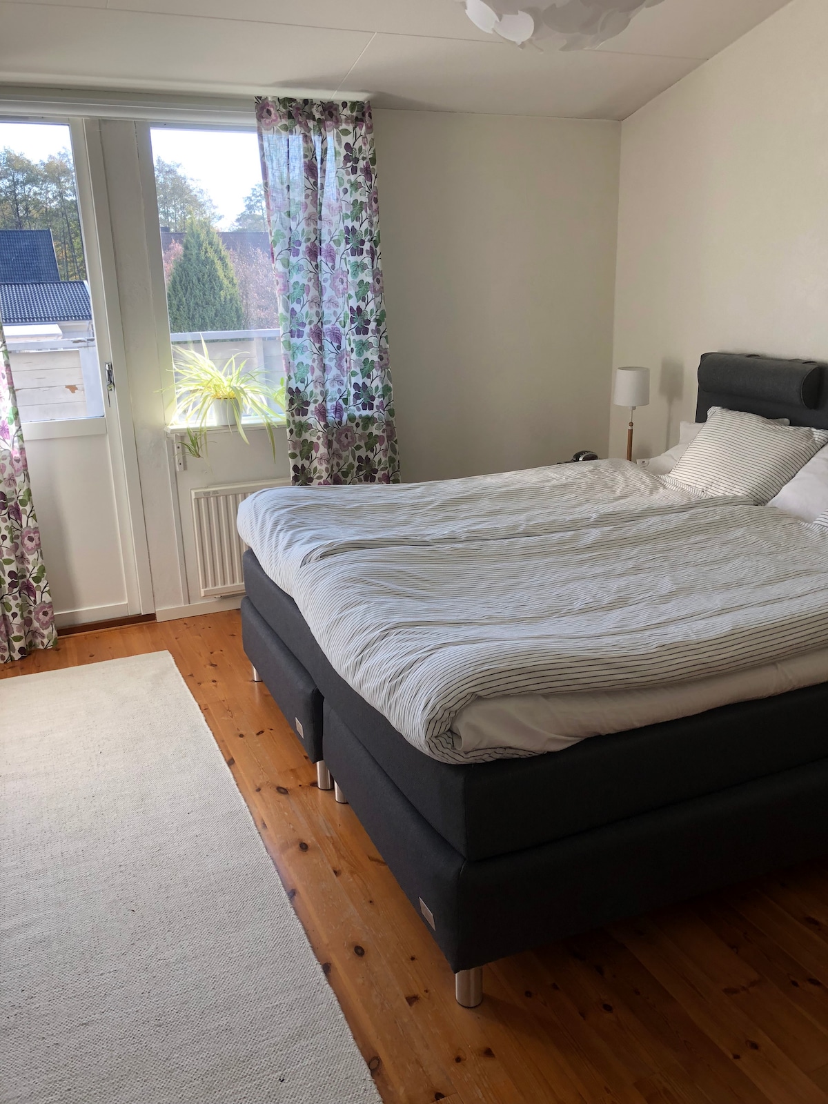 غرفة نوم 1 بسرير مزدوج ومخرج إلى الشرفة مع شمس الصباح.