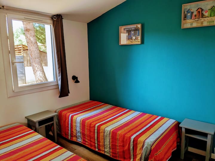 Chumba cha kulala vitanda viwili vya mtu mmoja vilivyo na stendi ya karibu na kabati la nguo.