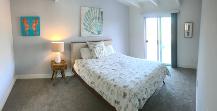 North Master suite: cama tamaño queen, colchón de espuma viscoelástica, techos de viga abierta de mediados de siglo, puerta corrediza al patio trasero. Ventilador en la esquina (no visible).