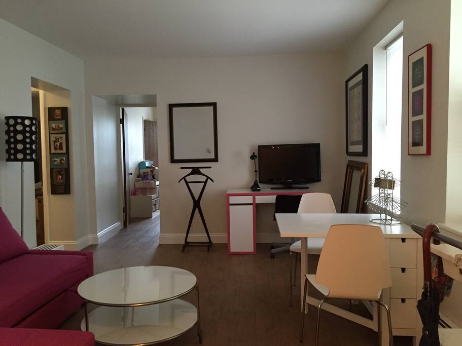 Living room, offers a convertible couch, desk, and collapsible dining table. The kitchen opens up to the living room.