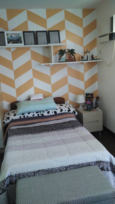 The bedroom has a single bed which can accommodate 2 at most. It has pillows, sheets, blanket and comforter. There is also a bedside table with lamp should you require a night light. Airconditioning unit and one electric fan unit are also available.