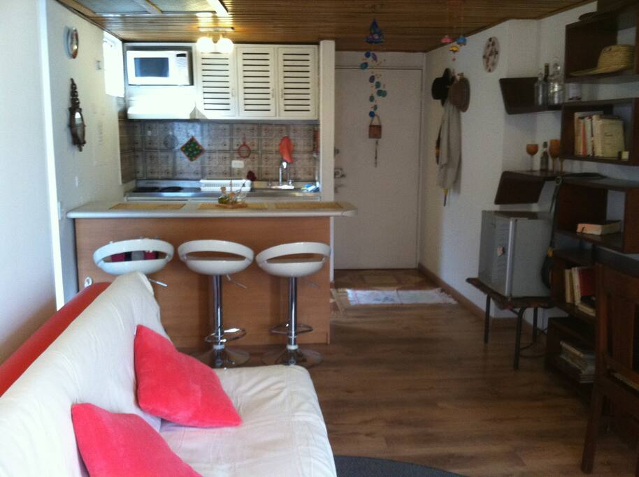 Cocina equipada con barra americana con tres puestos. Puerta de acceso al apartamento.