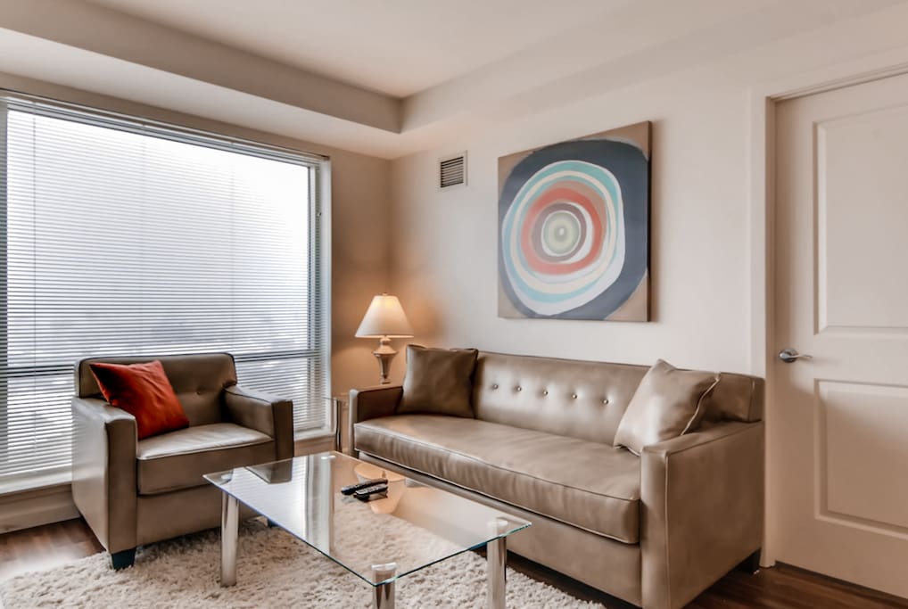 Comfortable living room with pullout sofa bed, club chair and floor to ceiling windows providing lovely natural light and views